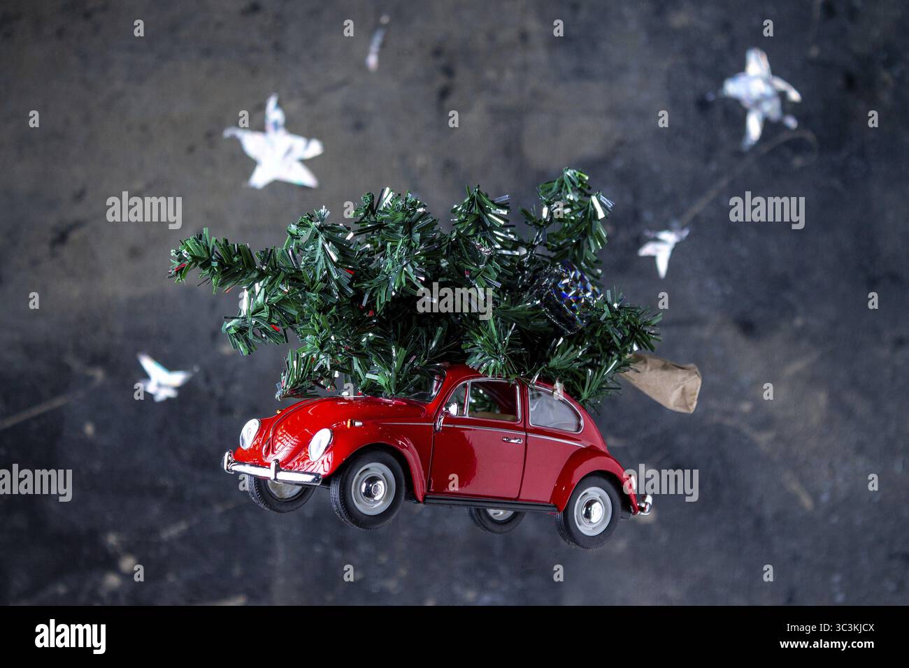Voiture rouge jouet avec un arbre sur le toit se précipite à travers le ciel étoilé de nuit Banque D'Images