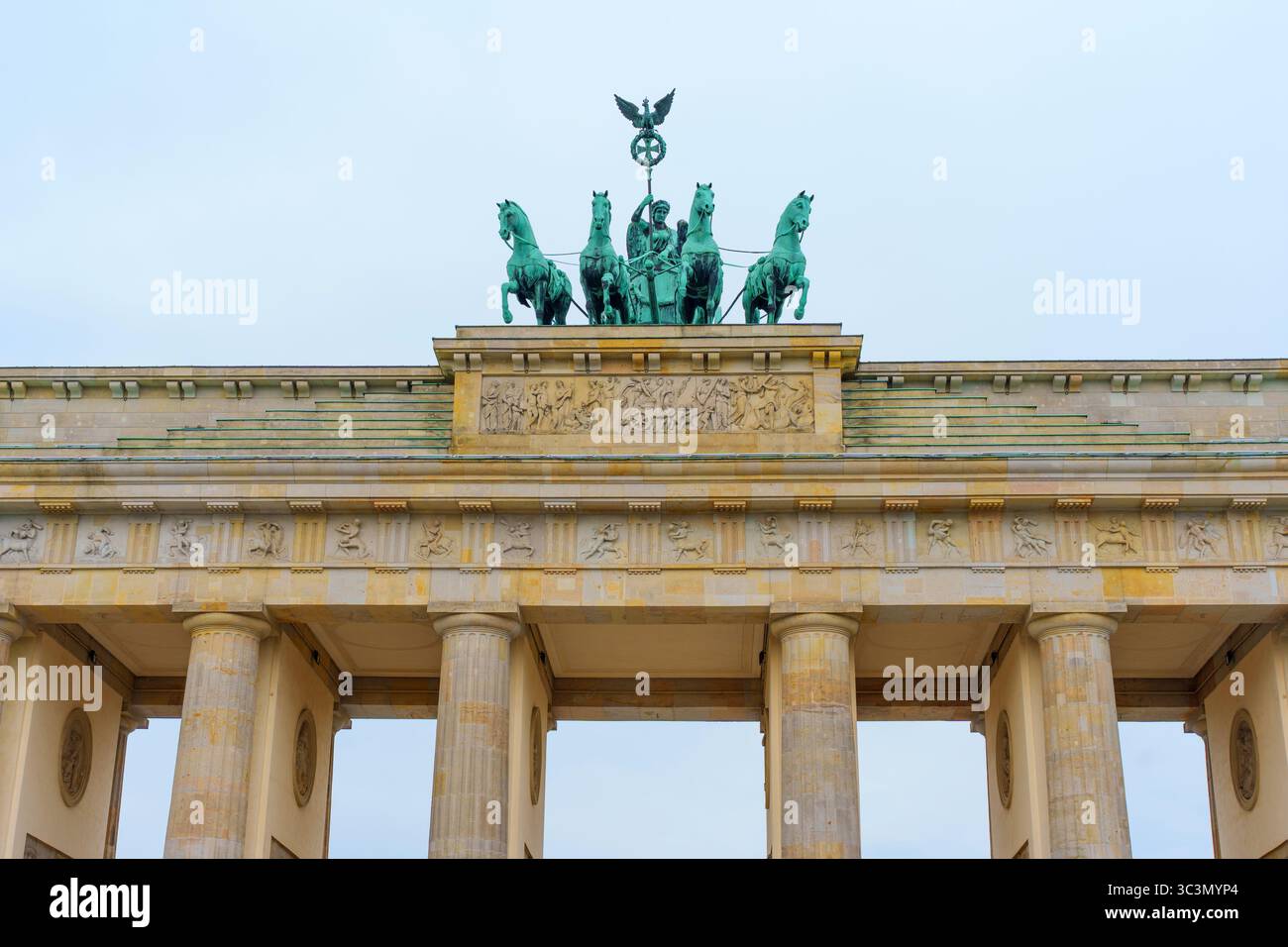 Berlin, Allemagne - 1er juin 2025 : porte de Brandebourg avec la sculpture emblématique quadriga au sommet, architecture classique, reliefs détaillés, ciel nuageux, B. Banque D'Images