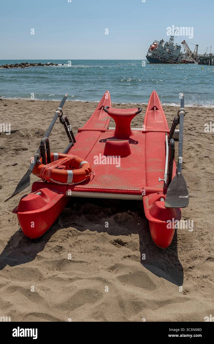Un canot de sauvetage rouge avec un navire incliné après avoir heurté la jetée en arrière-plan, Marina di Massa, Italie Banque D'Images