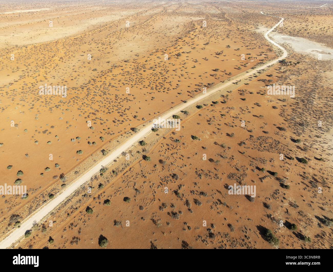 Vue aérienne d'une route solitaire tranchant le paysage aride, le chemin serrant vers l'horizon lointain, Walvis Bay, Namibie. Banque D'Images