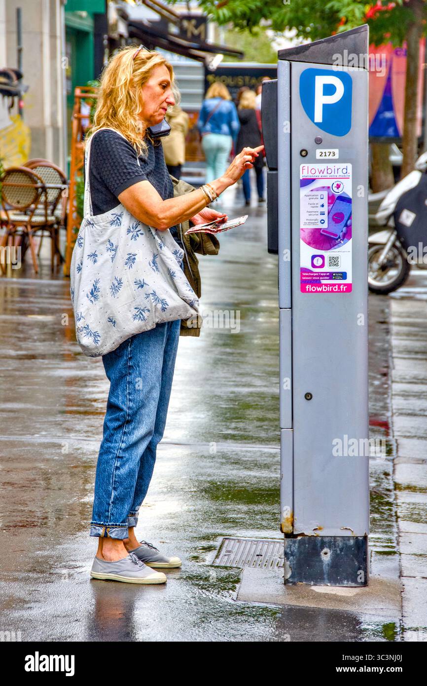 Femme utilisant un distributeur automatique de tickets de parcmètre - Tours, Indre-et-Loire (37), France. Banque D'Images
