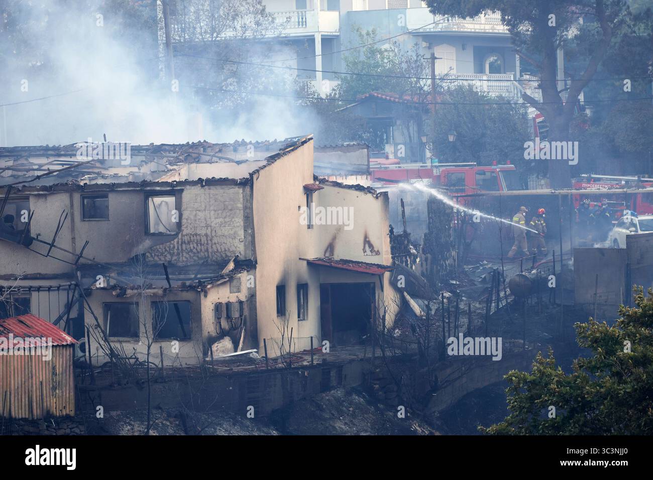Firefighters try to extinguish a fire at a house during a wildfire, in the northwestern suburb of Kryoneri, in Athens, Greece, Saturday, July 26, 2025. (AP Photo/Yorgos Karahalis) Banque D'Images