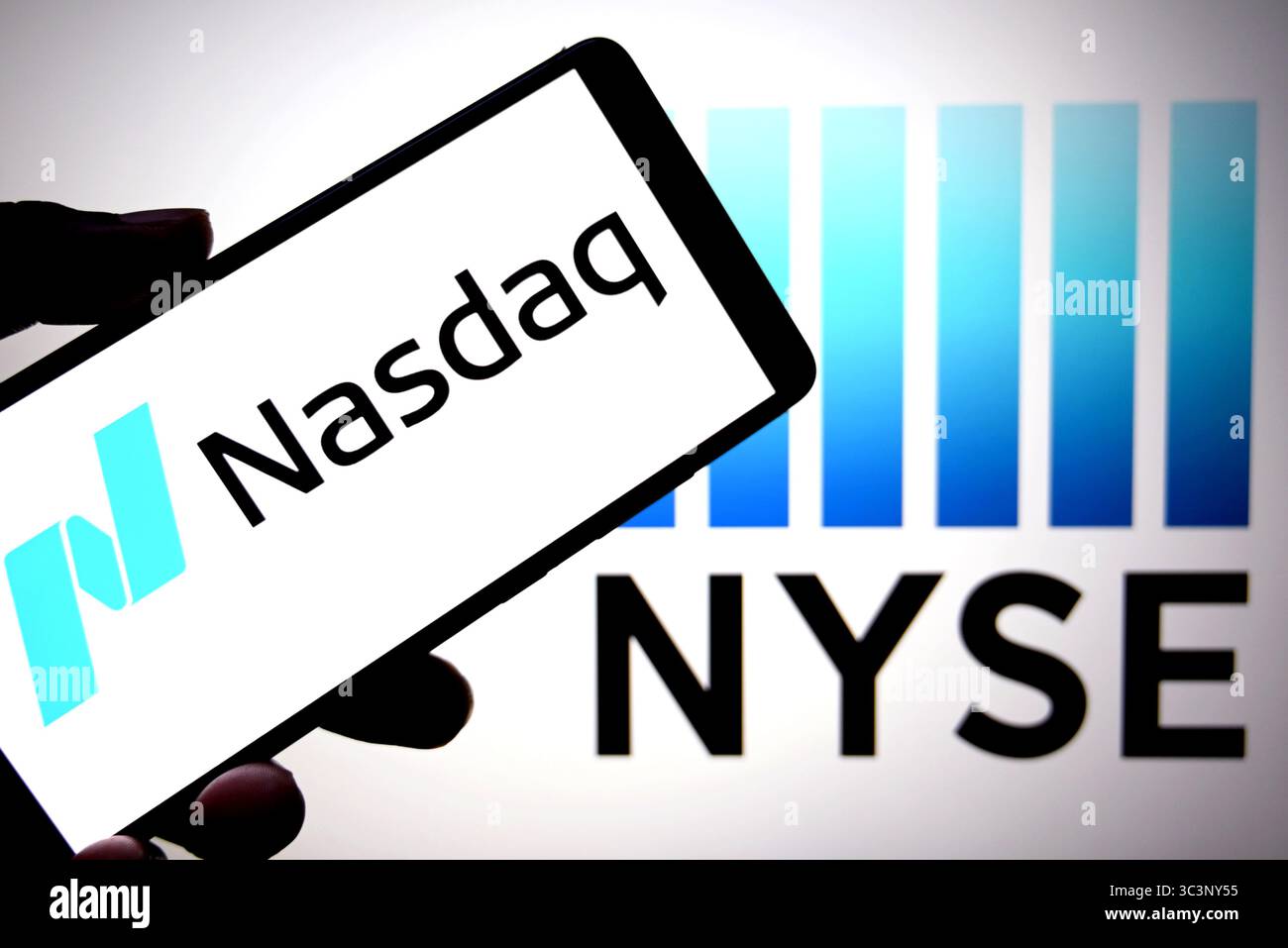 Dans cette illustration photo, un logo du NASDAQ est affiché sur un smartphone avec un logo NYSE (New York Stock Exchange) en arrière-plan. Banque D'Images