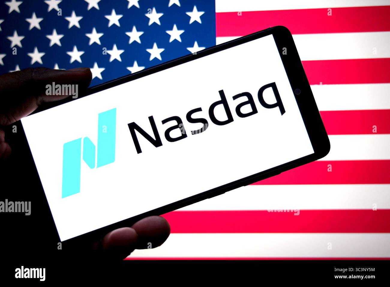 Dans cette illustration photo, un logo du NASDAQ est affiché sur un smartphone avec le drapeau américain en arrière-plan. Banque D'Images