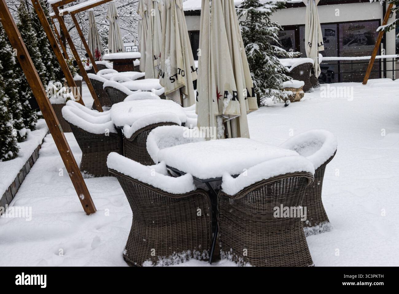 Café extérieur fermé en hiver. Tables et chaises d'un café en plein air recouvertes de neige. Banque D'Images