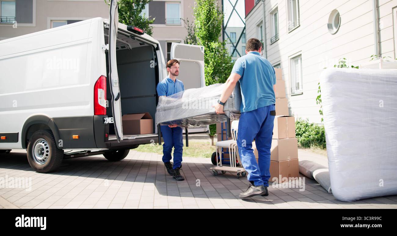Déménageurs hispaniques en camion de chargement uniforme bleu pour la livraison de meubles Banque D'Images