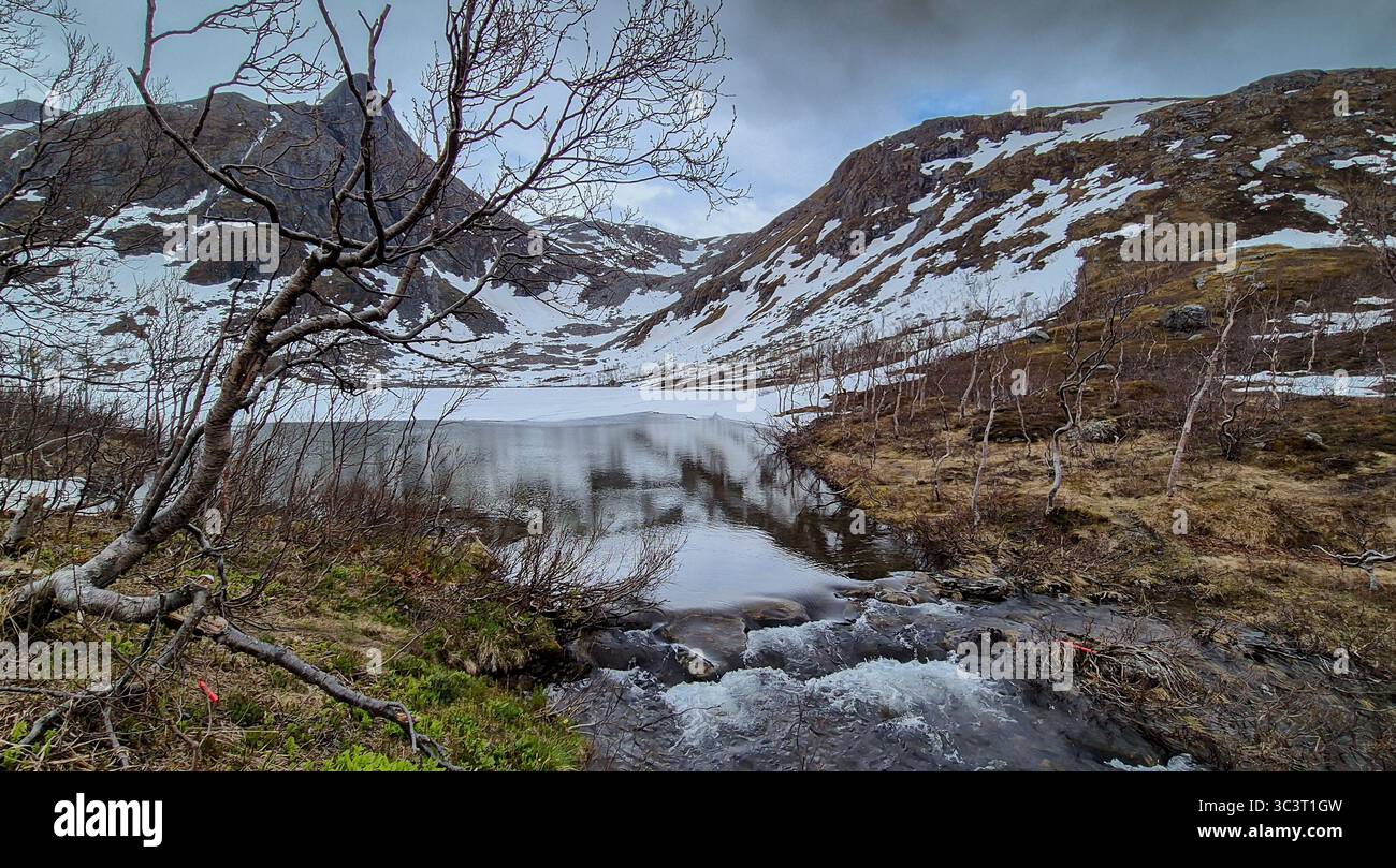Lac gelé et rivière sauvage avec cascade des montagnes enneigées sur l'île Senja en Norvège Banque D'Images