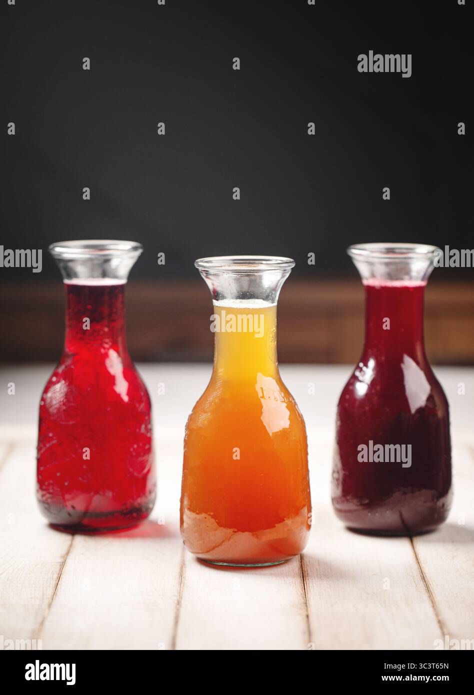 Carafes en verre avec jus d'orange rouge et violet Banque D'Images