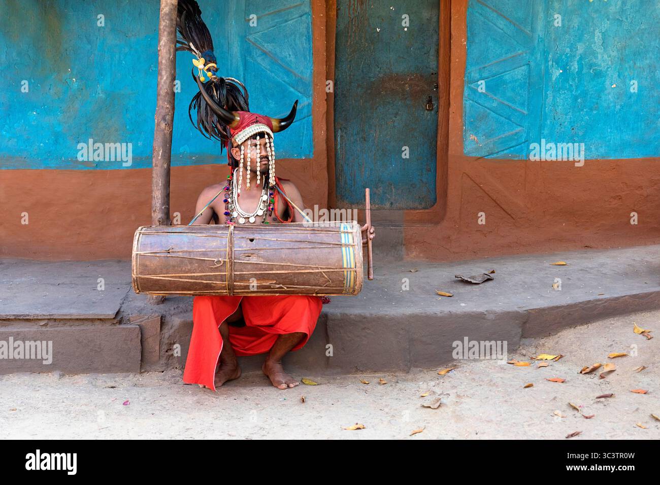 Homme en costume traditionnel de la tribu Bison-Horn Maria assis devant une petite maison pittoresque dans un village dans la région de bastar, Chhattisgarh Banque D'Images