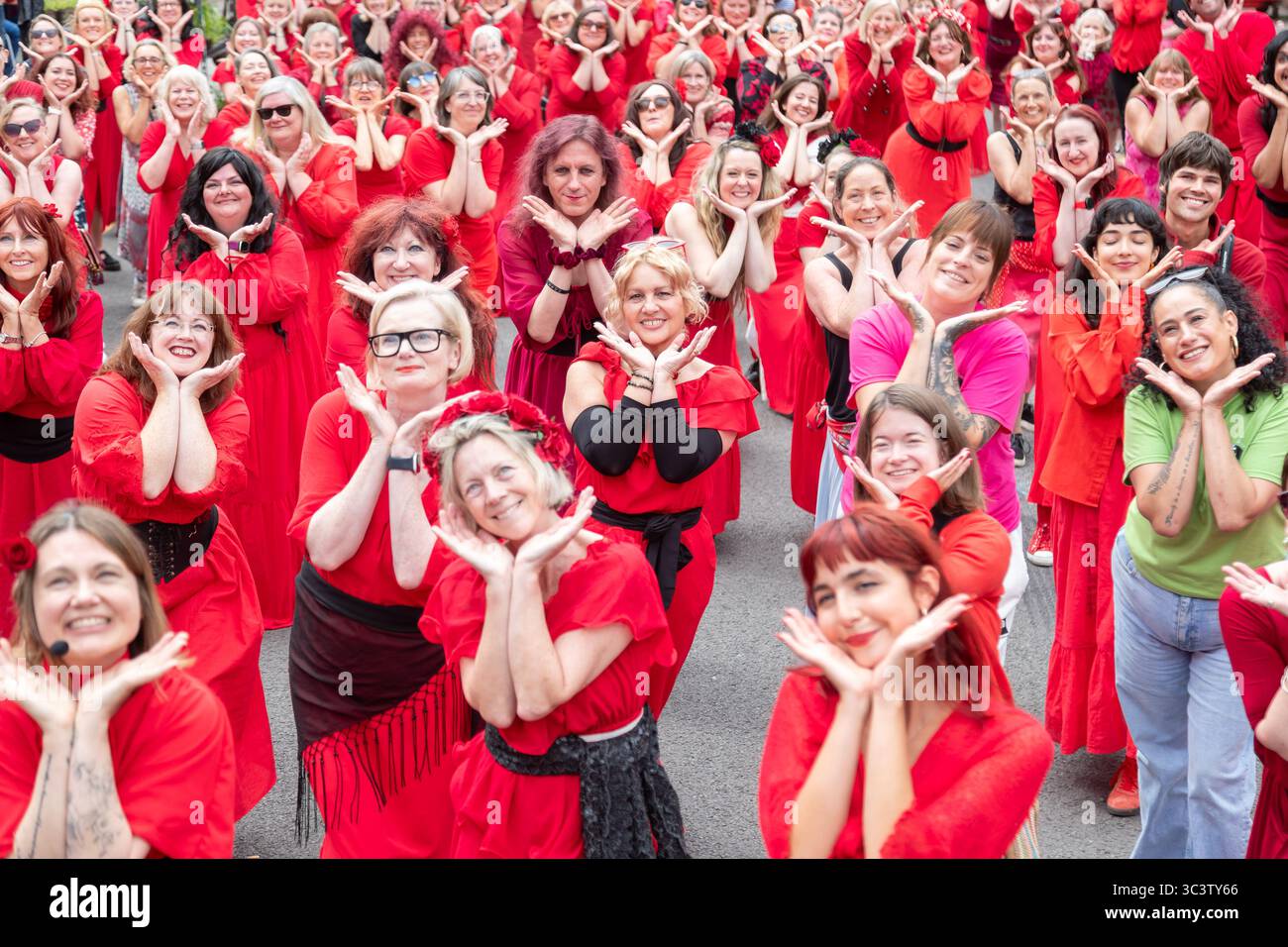 Birmingham, Royaume-Uni. 27 juillet 2025. Trois cents personnes se réunissent pour exécuter une routine de danse appelée Most Wuthering Heights Ever à Kings Heath, Birmingham, Royaume-Uni. Les participants, tous vêtus de rouge, ont été adressés par Jess Phillips, députée travailliste de Yardley, Birmingham, avant de recréer le clip de la chanson emblématique de Kate Bush, « Wuthering Heights ». L'événement amasse des fonds pour les éducatrices d'autonomisation des femmes et de rétablissement et les associations caritatives ANAWIM. Crédit : Peter Lopeman/Alamy Live News Banque D'Images