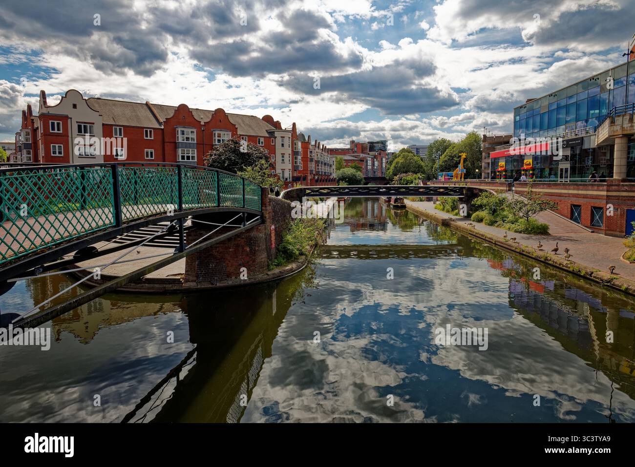 Ponts sur un canal avec des appartements résidentiels sur une rive et Legoland en arrière-plan dans le centre-ville de Birmingham, en Angleterre. Banque D'Images