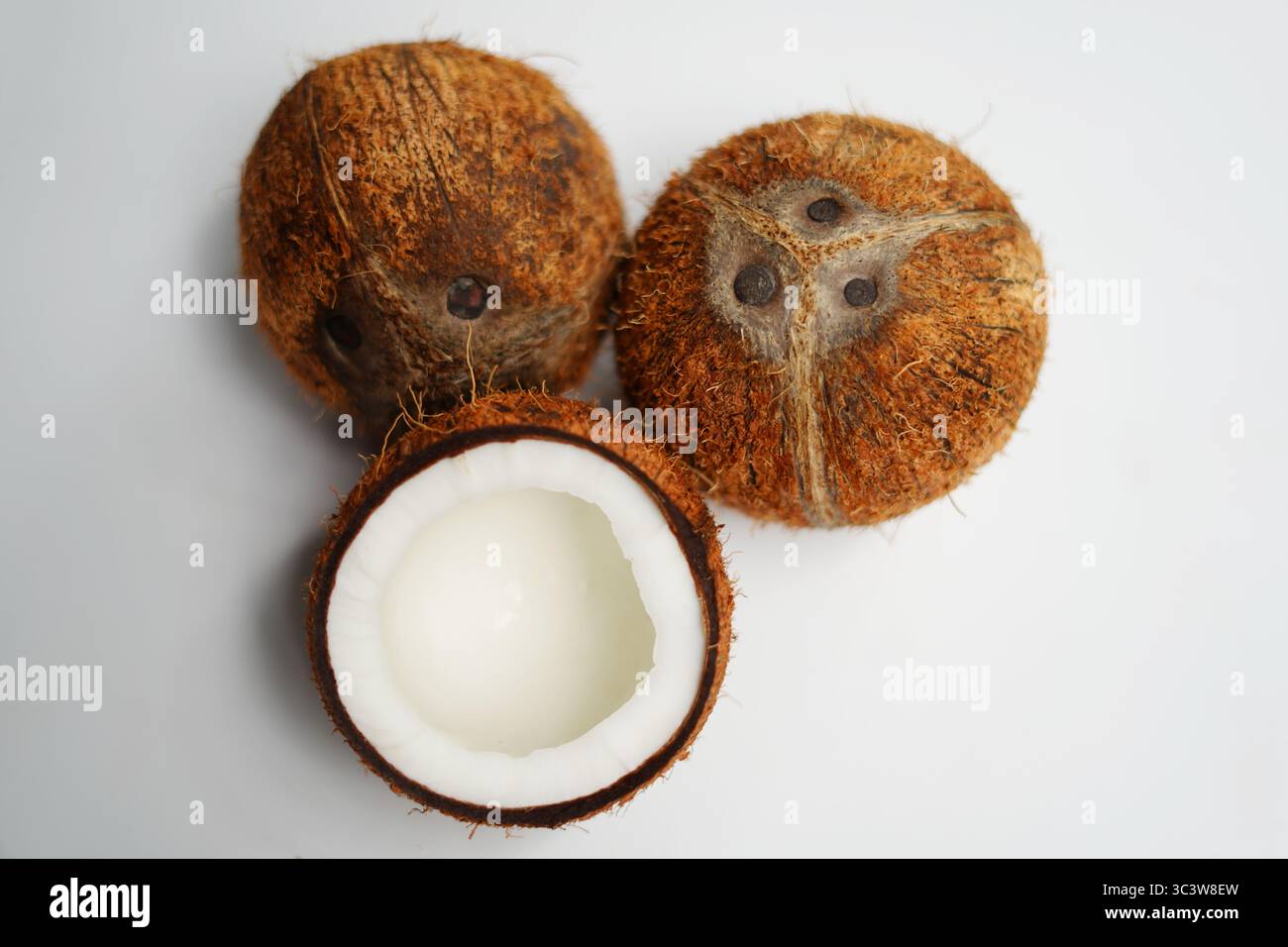 La moitié de noix de coco et deux noix de coco isolées sur fond blanc. Banque D'Images