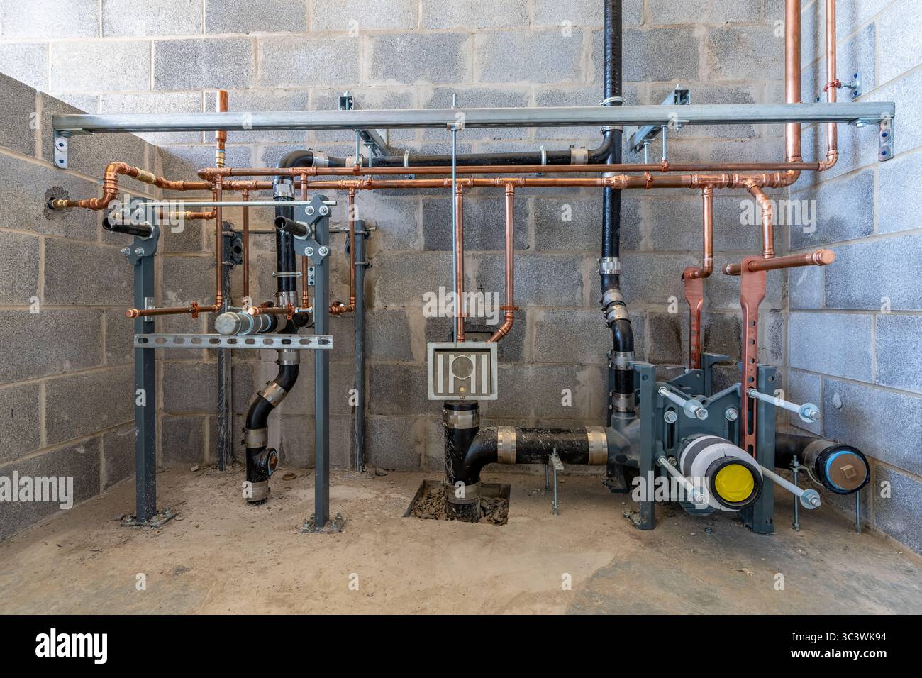 Plomberie rugueuse pour une nouvelle salle de bain commerciale avec un mur de bloc. Banque D'Images