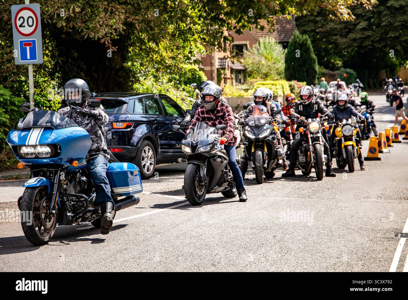 Les motocyclistes en équipement de protection se rassemblent dans un convoi coloré au Calne Bike Meet pour un événement de randonnée de groupe sous un ciel dégagé. Banque D'Images