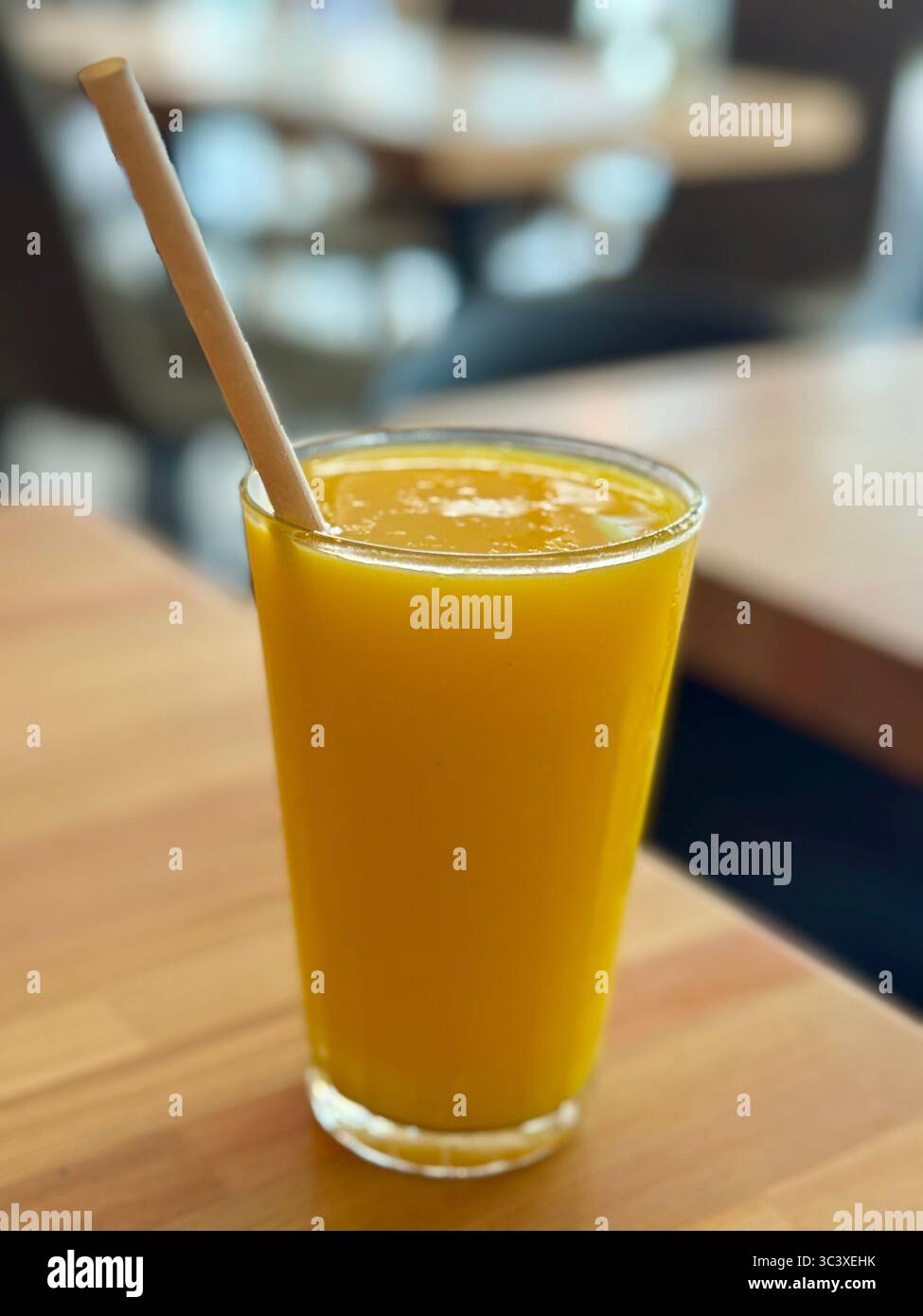 Jus d'orange frais servi dans un verre clair avec une paille, Lübeck, Allemagne. - Image de stock capturée avec un smartphone
