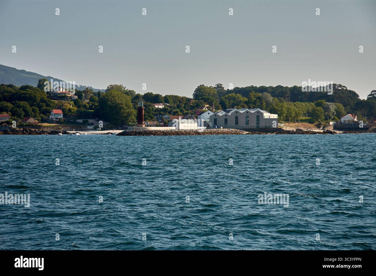 Le Museum do Mar de Galicia à Vigo se dresse le long de la côte atlantique, entouré de végétation, accompagné d'un phare historique. Banque D'Images