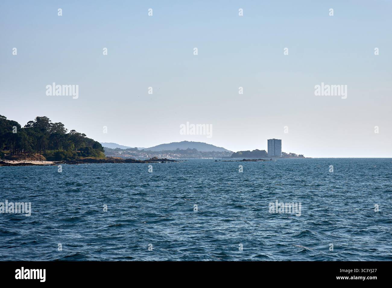 L'horizon marin s'étend vers l'île de Toralla à Vigo, avec sa tour résidentielle qui se dresse contre la végétation côtière. Banque D'Images