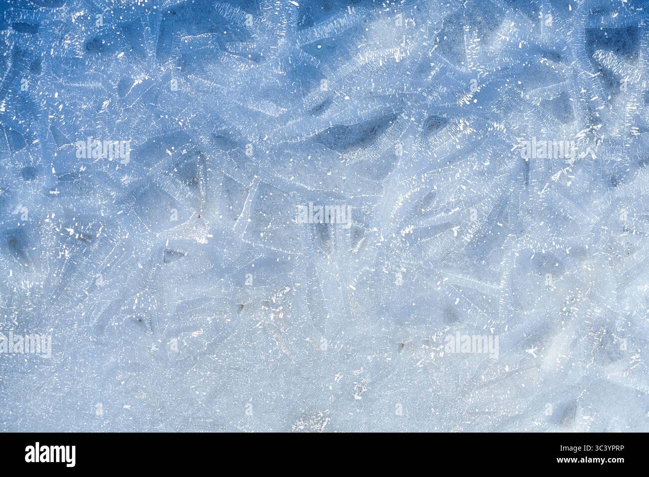 Gros plan de la surface de glace texturée avec des marques de neige et de rayures, un fond hivernal ou un résumé saisonnier Banque D'Images