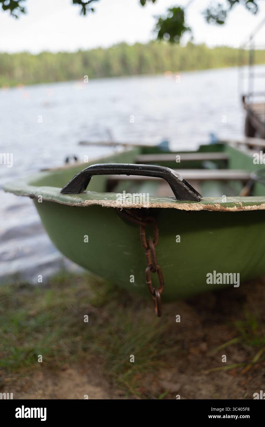 Un bateau vert qui dispose d'une chaîne robuste solidement attachée à lui, ajoutant un élément de sécurité et de fonctionnalité à l'embarcation Banque D'Images
