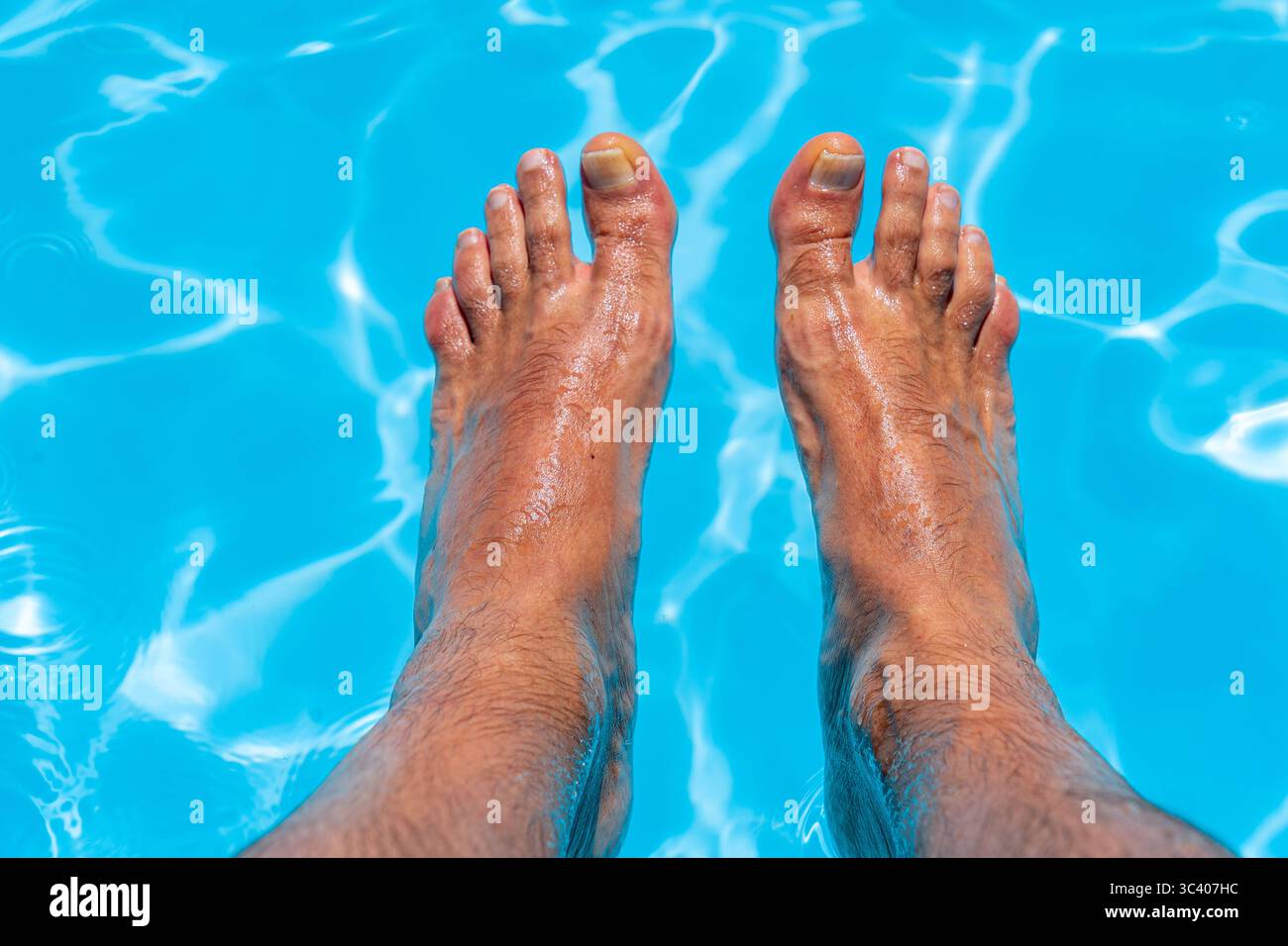 Beaux pieds avec 30 centimètres d'homme blanc caucasien à l'intérieur de l'eau bleue et de la piscine Banque D'Images