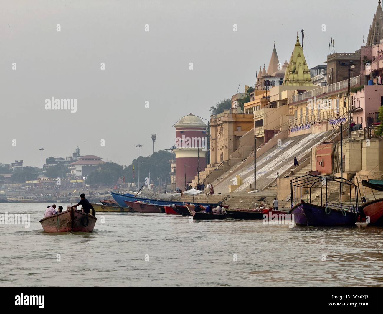 Bâtiments historiques et bateaux le long d'une rivière, atmosphère paisible avec lumière douce du jour, Ganges, Varanasi, Uttar Pradesh, Inde Banque D'Images