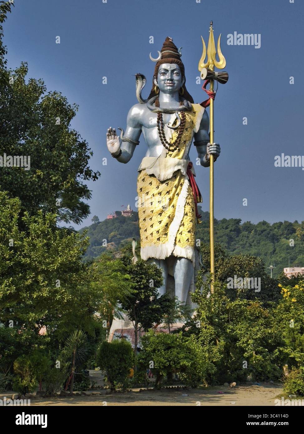 Grande statue de Shiva avec trident devant la colline boisée, fort contraste visuel entre la statue et la nature, Swami Vivekanand Park, Haridwar, Uttarakhan Banque D'Images