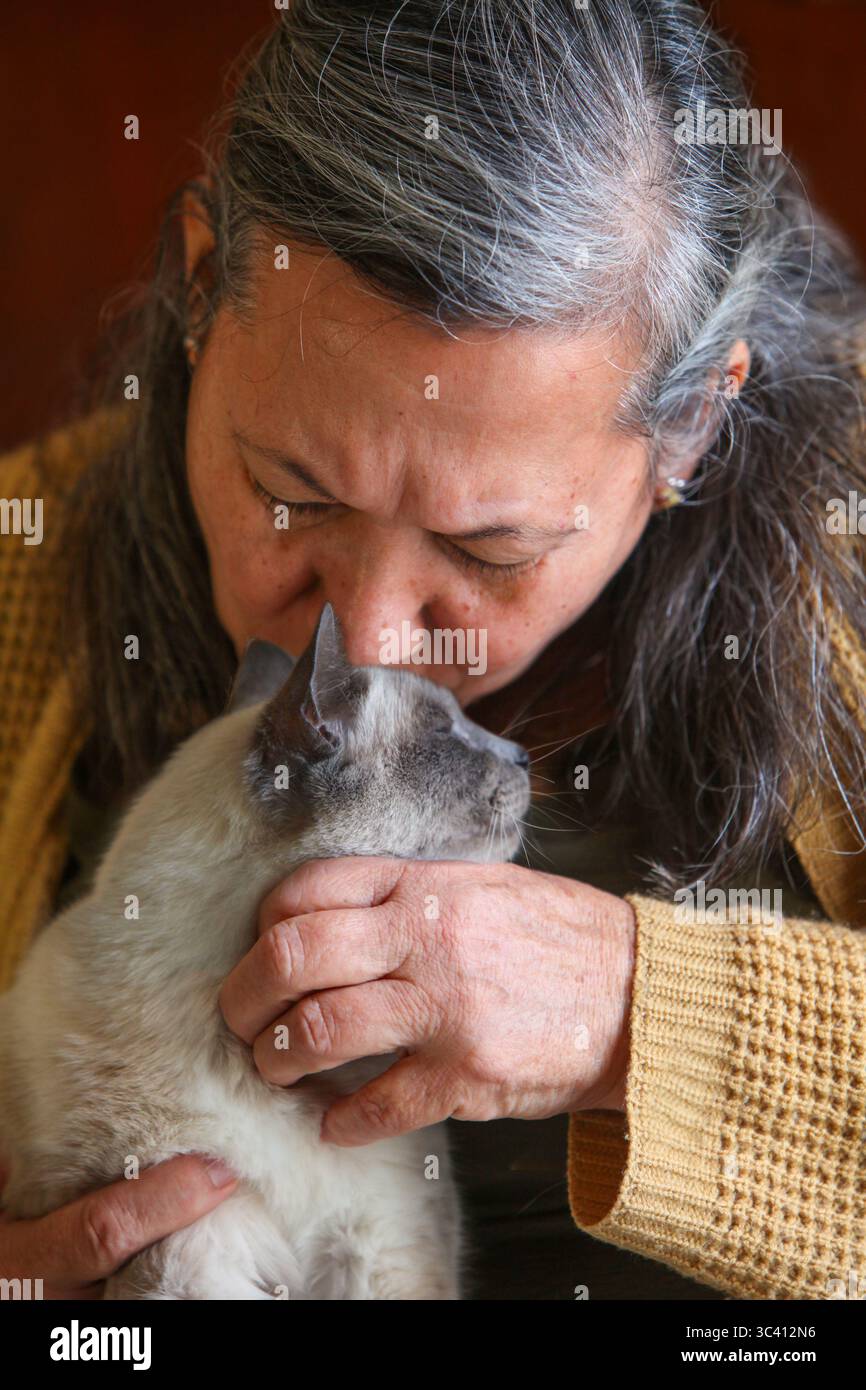 gros plan portrait d'une femme âgée latino tenant avec amour son chat à l'intérieur Banque D'Images
