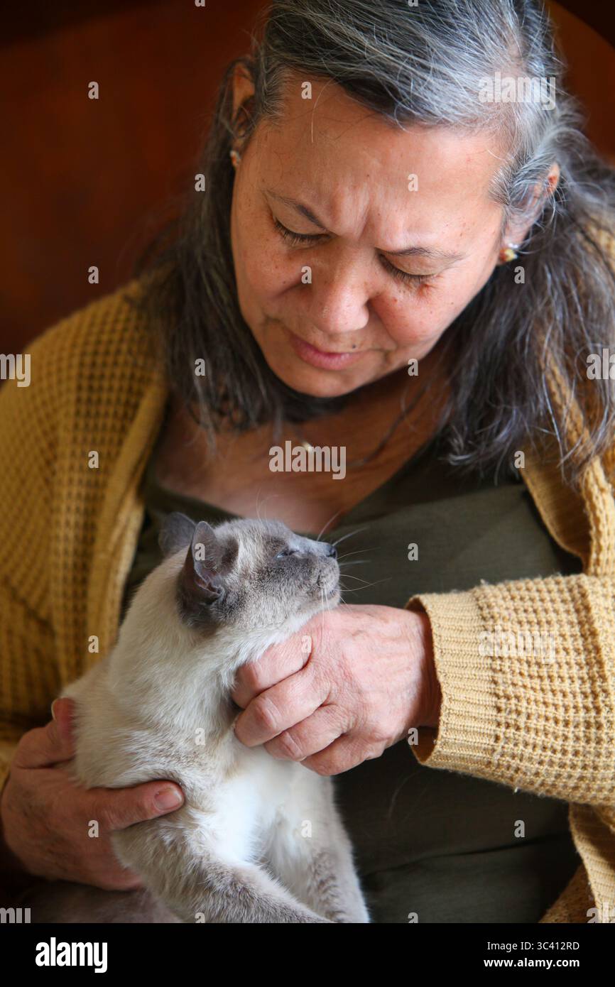 gros plan portrait d'une femme âgée latino tenant avec amour son chat à l'intérieur Banque D'Images