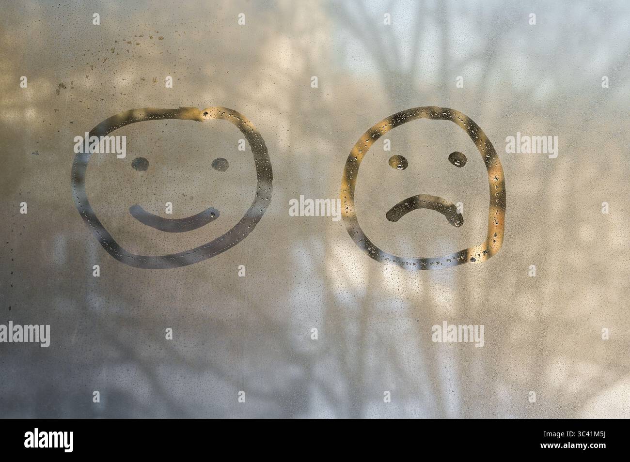 finger art verre de fenêtre vapeur - visages heureux et tristes côte à côte. duo reflète les émotions humaines fugaces. L'humeur de quelqu'un saute des émoticônes heureuses et tristes Banque D'Images