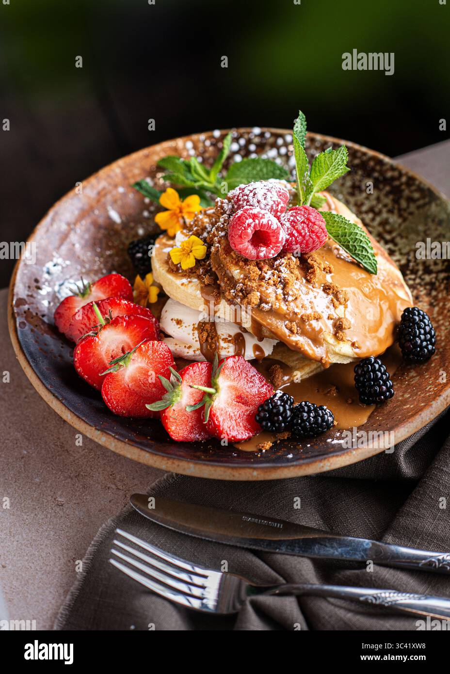 Pile de délicieuses crêpes garnies de crème fouettée et de baies fraîches, joliment décorées de fruits. Savoureux petit déjeuner fait maison. Banque D'Images
