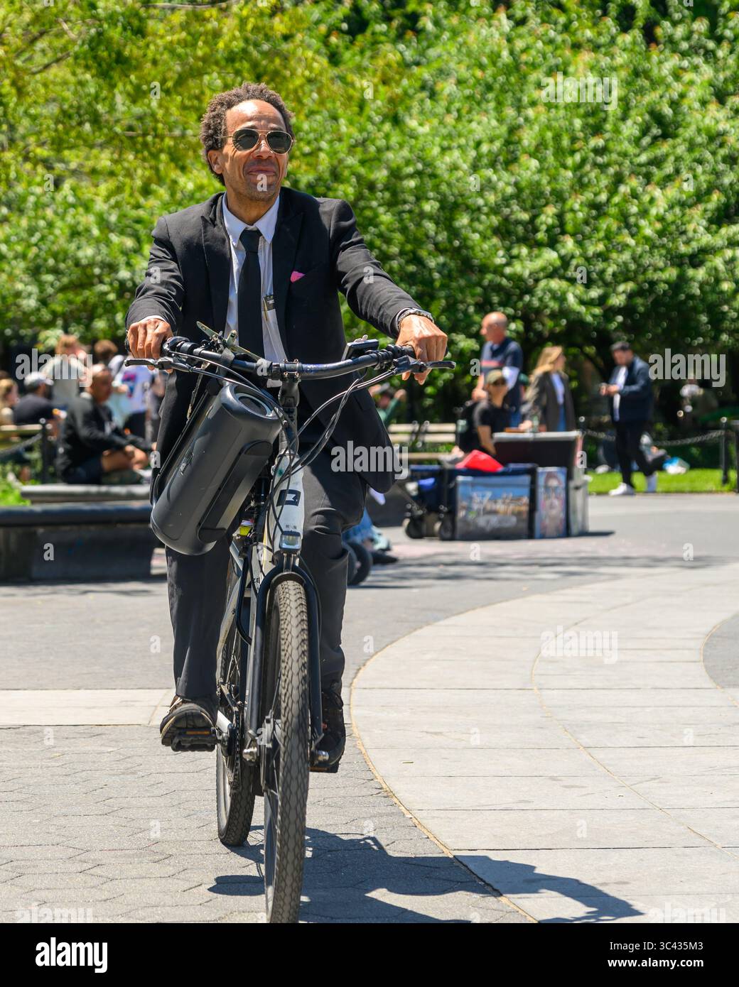 Un homme heureux, excentrique et adapté écoute sa Boombox tout en circulant à vélo dans Washington Square Park, New York. Banque D'Images
