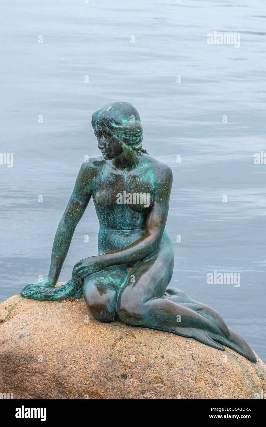 La statue emblématique de la petite Sirène se trouve gracieusement sur un rocher à Copenhague, au Danemark. Entouré par des eaux tranquilles, il offre une vue sereine pour les visiteurs. Banque D'Images
