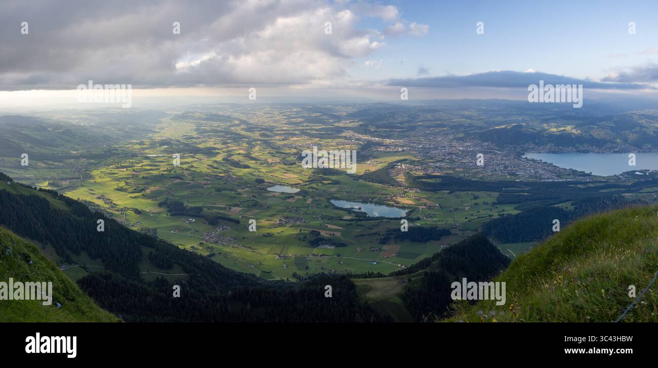 Une vue panoramique imprenable met en valeur la luxuriante vallée de Simmental en Suisse, baignée par la lumière douce du soleil filtrant à travers les nuages dispersés. La vallée f Banque D'Images