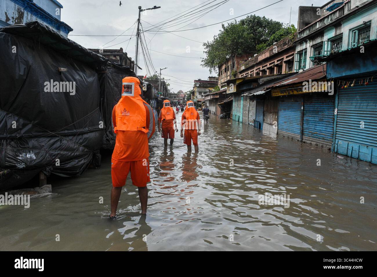 26 mai 2021, Kolkata, Bengale occidental, Inde : portant des masques orange avec des capuches, des officiers du Groupe indien de gestion des catastrophes patrouillent une rue inondée causée par la marée haute sur le fleuve Gange couplée au cyclone Yaas, à Kolkata. Le cyclone Yaas a touché terre en fin d'après-midi mercredi sur la côte est de l'Inde, causant des dommages massifs aux zones côtières et fluviales de l'Odisha et du Bengale. (Crédit image : © Debarchan Chatterjee/ZUMA Wire) Banque D'Images