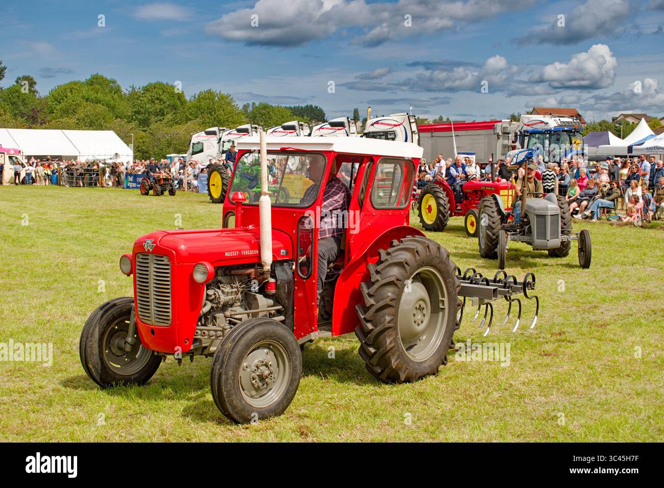 Salon agricole de Nairn Moray Écosse juillet 2025 soleil et un tracteur et chauffeur Massey Ferguson Banque D'Images