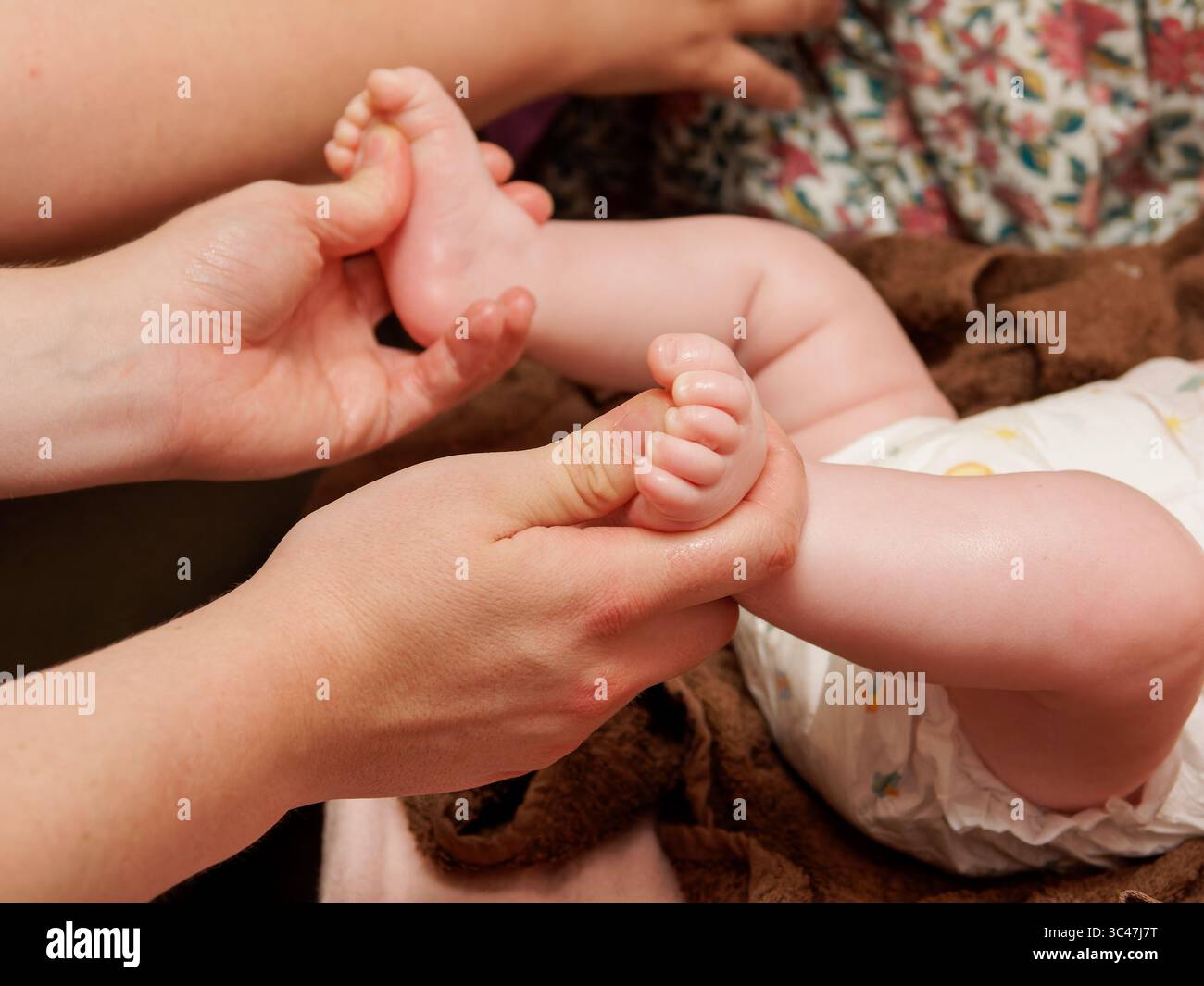 Gros plan sur le massage des pieds de bébé pendant la séance de thalassothérapie spa, soins de bien-être et de relaxation pour bébé. Banque D'Images