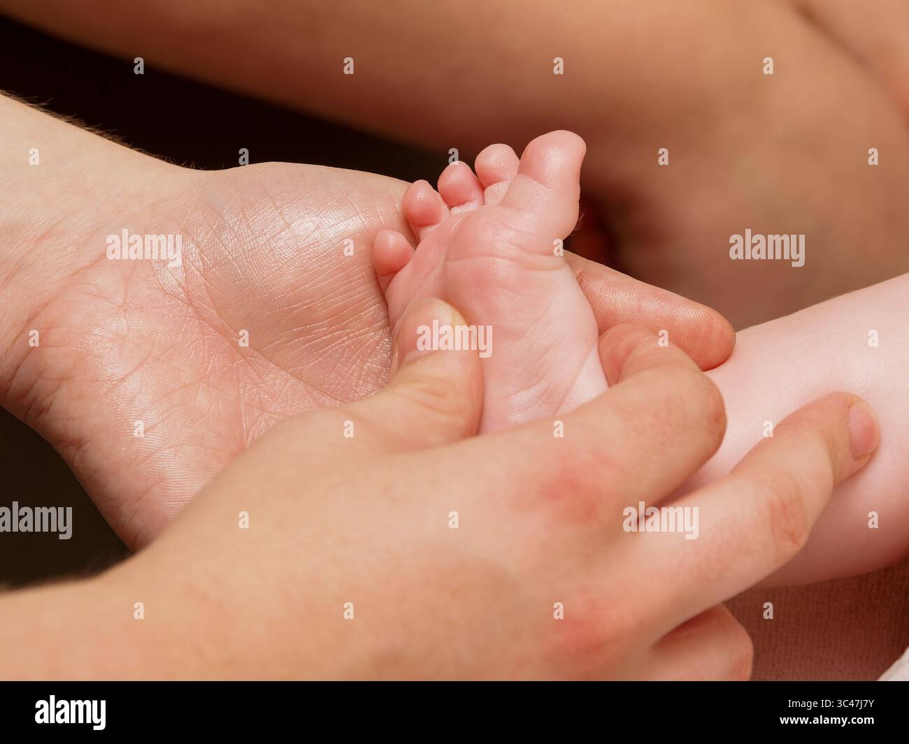 Gros plan sur le massage des pieds de bébé pendant les soins de thalassothérapie spa, le bien-être du nourrisson et la thérapie de relaxation. Banque D'Images