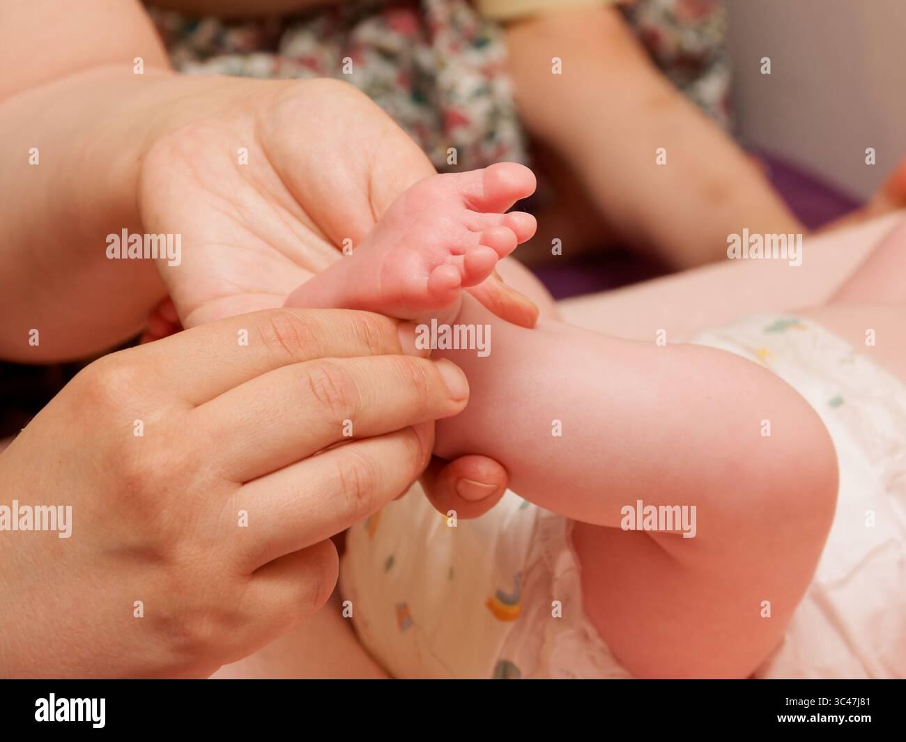 Gros plan sur le massage des pieds du nouveau-né pendant les soins de thalassothérapie, le bien-être du bébé et la thérapie de relaxation. Banque D'Images