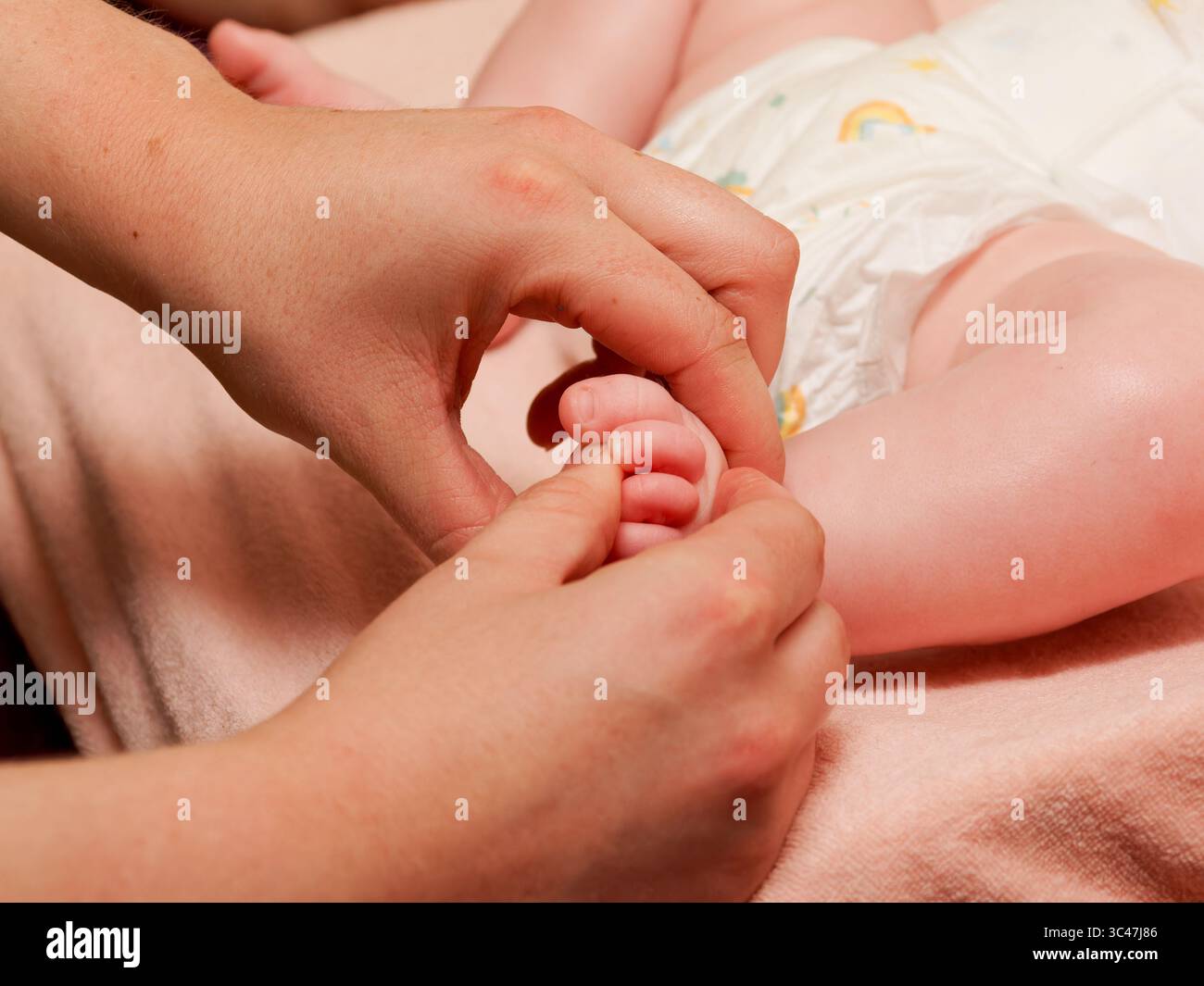 Gros plan sur le massage des orteils de bébé pendant la séance de thalassothérapie spa, soins de bien-être et de relaxation pour bébé. Banque D'Images