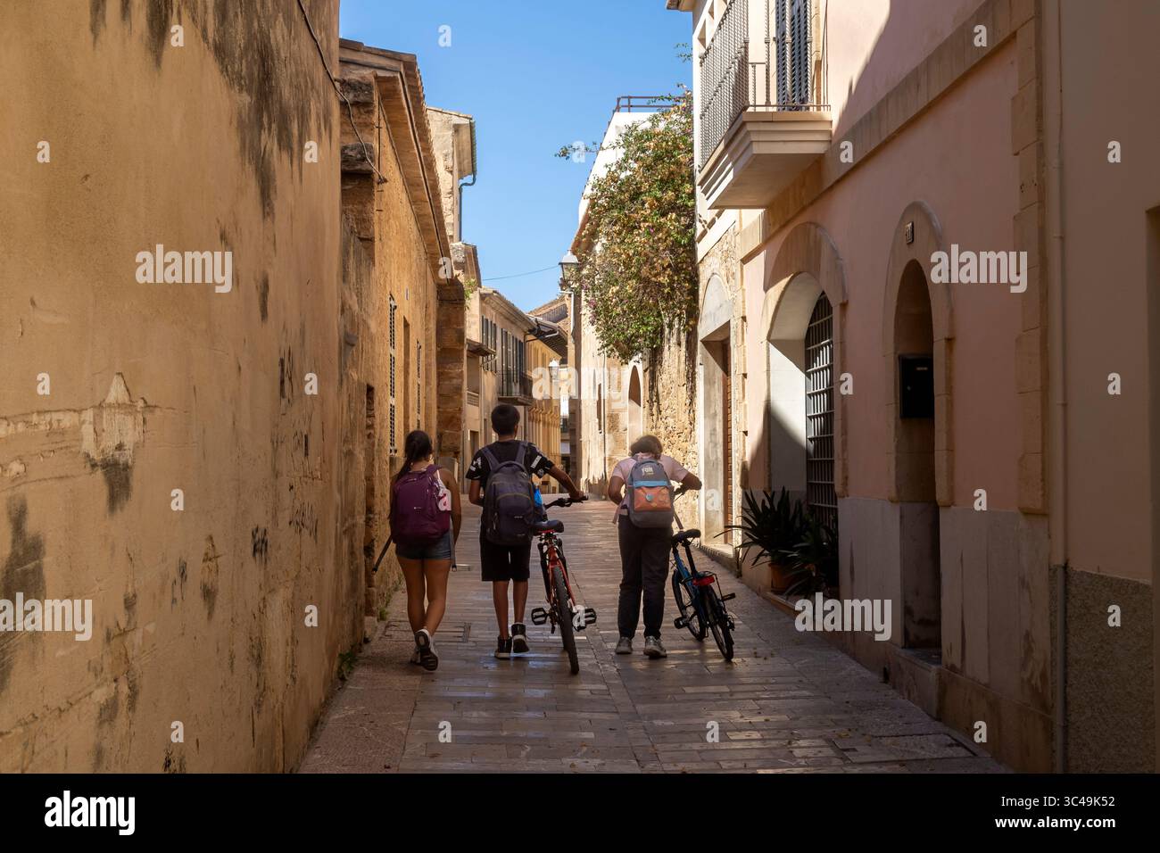 Trois enfants marchant à la maison de l'école, Alcúdia Historic Old Towm, Majorque, Îles Baléares, Espagne Banque D'Images