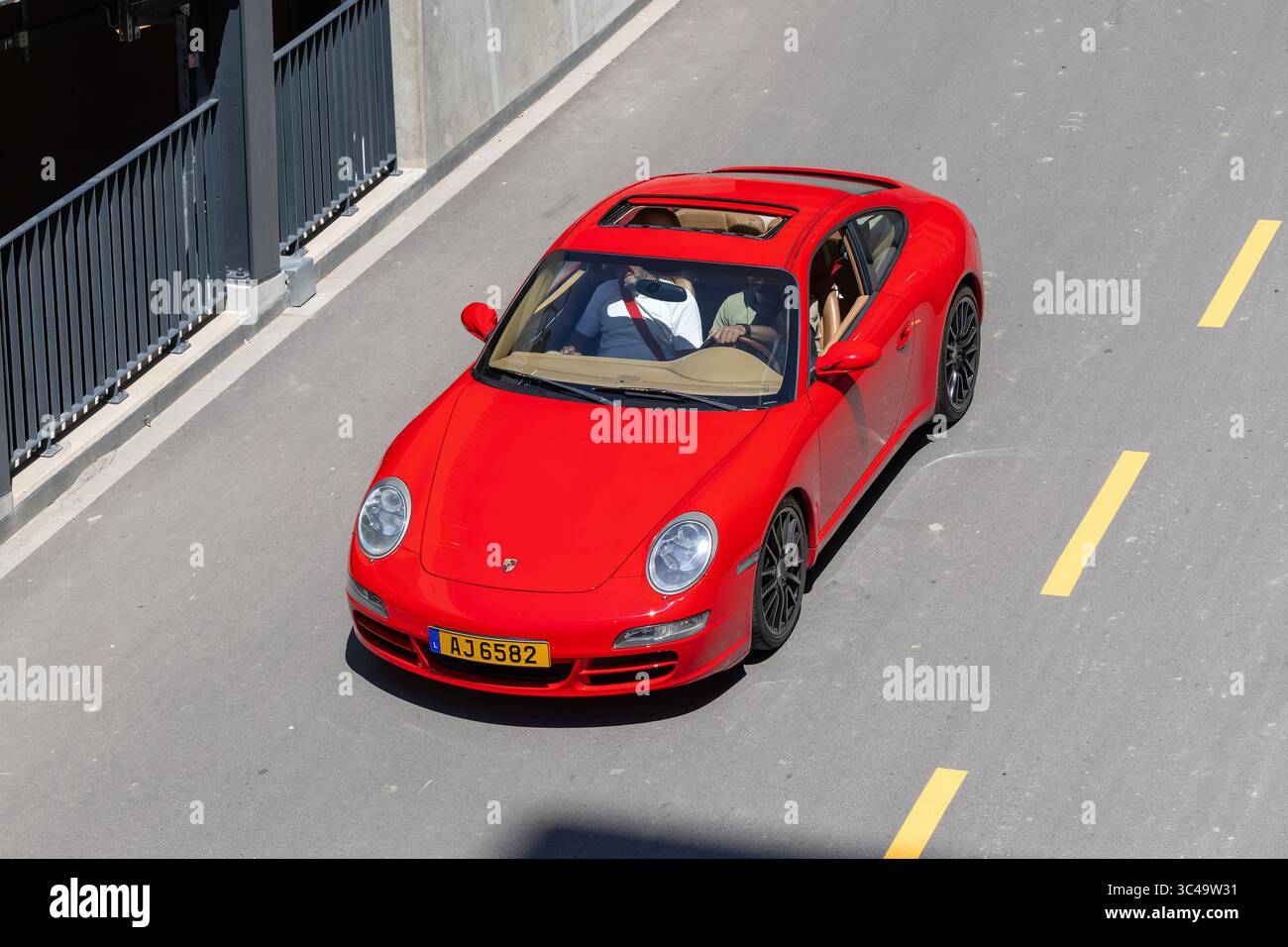Wickrange, Luxembourg - vue sur une Porsche 997 Carrera S rouge conduisant dans une rue vue d'en haut. Banque D'Images