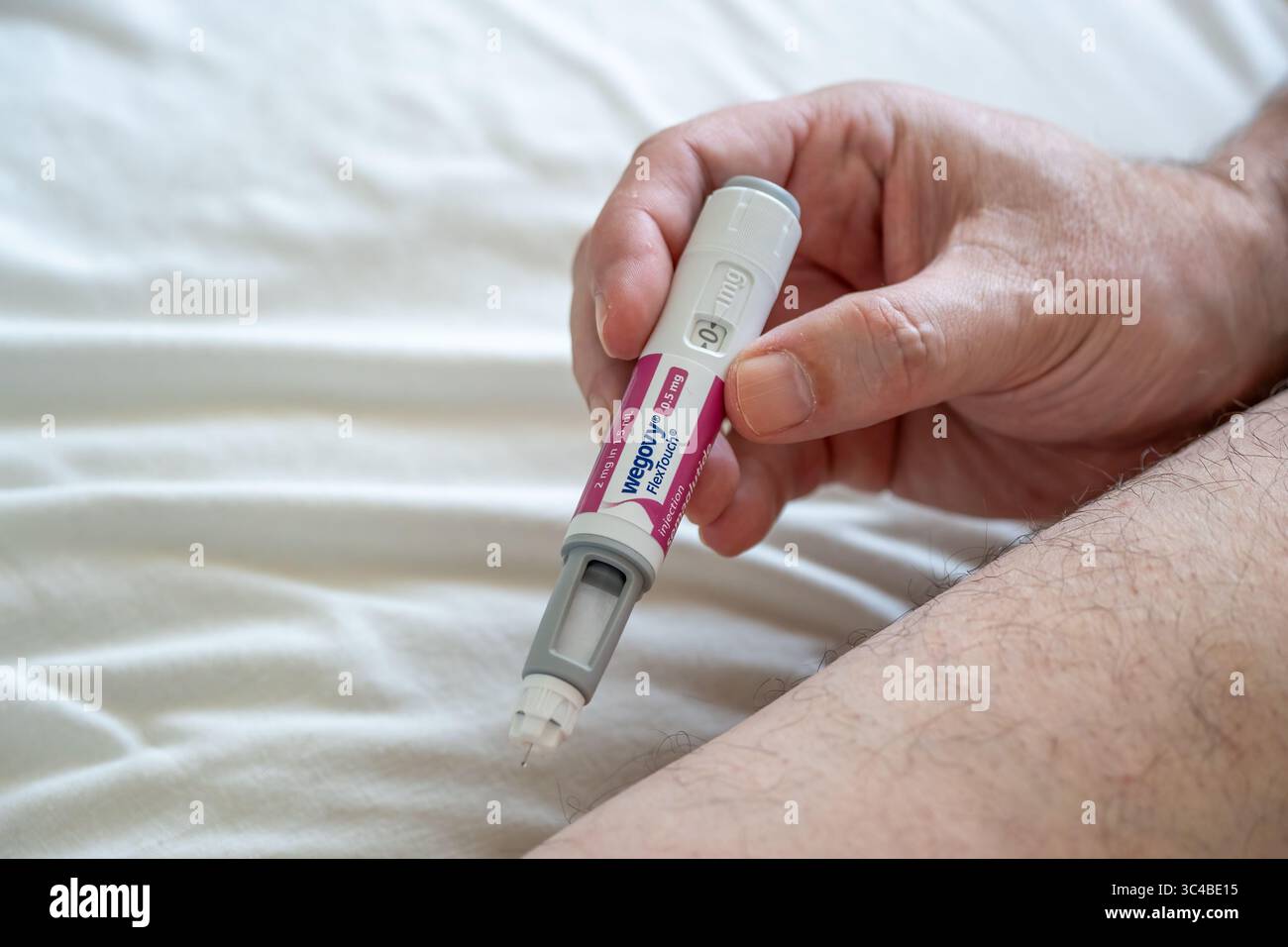 Homme utilisant un stylo injectable Wegovy pour le traitement de perte de poids, en administrant une dose sous-cutanée dans la cuisse. Concept de prise en charge de l'obésité et de la santé. Banque D'Images
