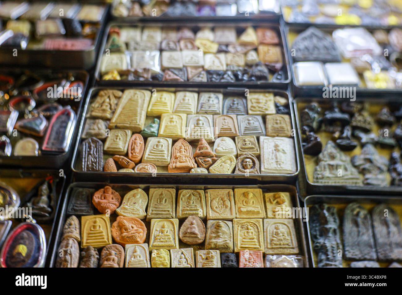Une vue nocturne des amulettes de Bouddha thaïlandais exposées dans des boîtes sur un marché local. Les articles représentent un mélange de croyance spirituelle et de culture thaïlandaise traditionnelle Banque D'Images