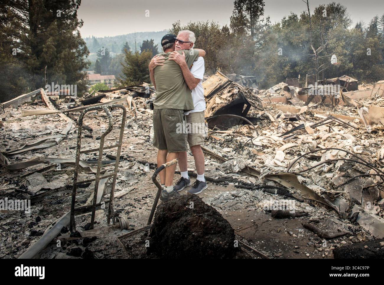 27 juillet 2018 - Redding, Californie, États-Unis - DAN SPRAGGINS, 79 ans, à droite, de Lake Redding Estates, reçoit un câlin de son ami DAVID, qui ne voulait pas donner son nom de famille, sur les restes brûlés de sa maison. 'Elle ne sera pas bonne quand je lui montrerai des photos de cet endroit.... C'était une belle maison. » Spraggins a dit qu'il avait annoncé la nouvelle à sa femme Chris. L'incendie de Carr dans le comté de Shasta a rasé des dizaines de maisons dans la région de Redding, tué deux personnes et forcé l'évacuation de plus de 37 000 personnes après qu'il a sauté la rivière Sacramento. (Crédit image : © Hector Amezcua/Sacramento Bee via Banque D'Images
