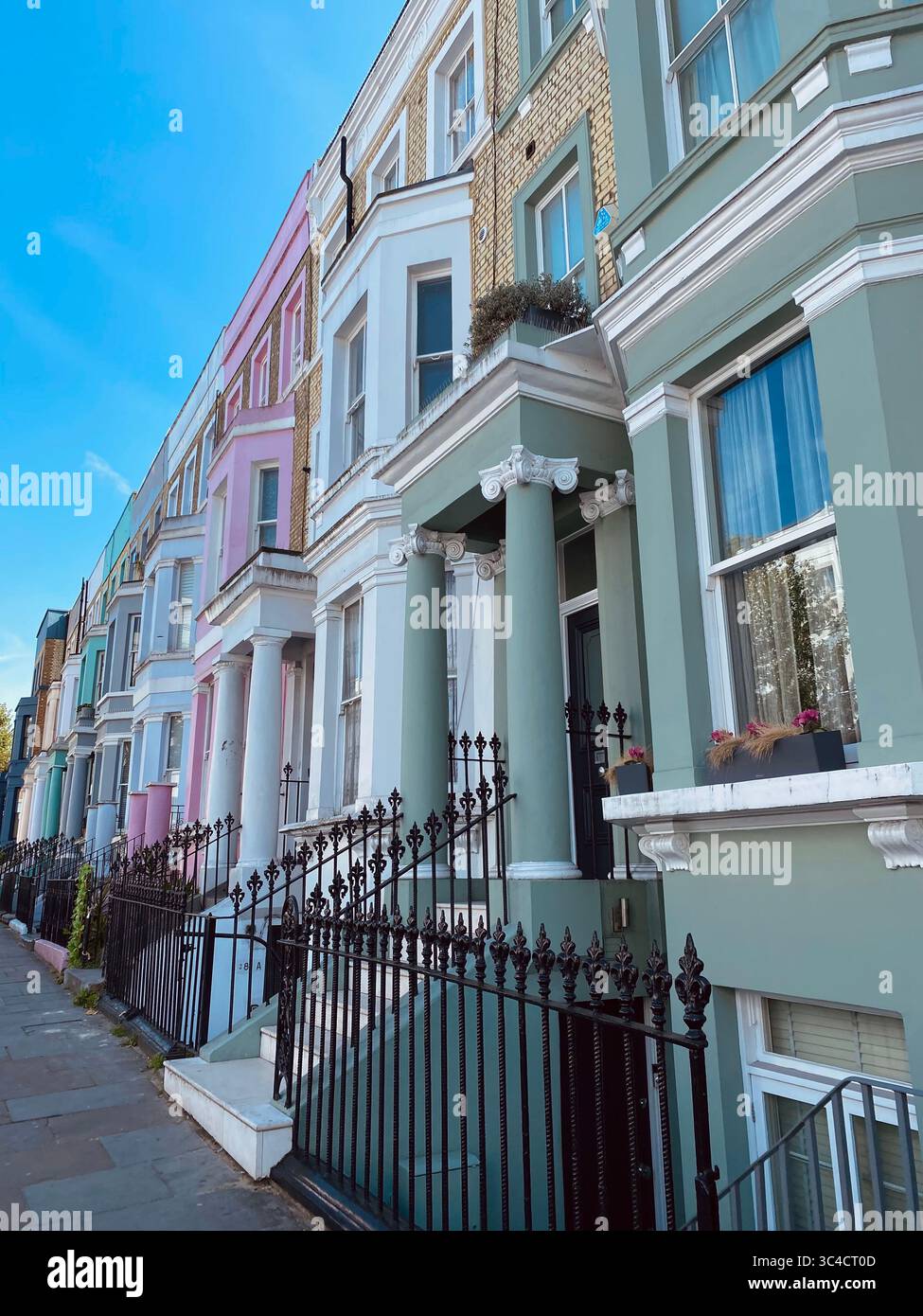 Des maisons colorées bordent une rue ensoleillée de Notting Hill, Londres, présentant une architecture emblématique et un charme estival dynamique dans ce célèbre quartier. - Image de stock capturée avec un smartphone