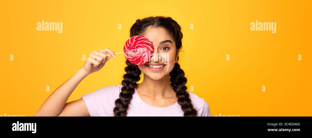 Femme indienne tenant une lollipop, couvrant un oeil avec des bonbons Banque D'Images