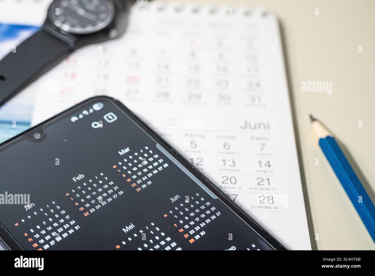 Calendrier de bureau avec crayon, marqueur et smartphone affichant le calendrier numérique. Idéal pour les blogs de productivité, les applications de planification, la gestion du temps ou le mode Banque D'Images