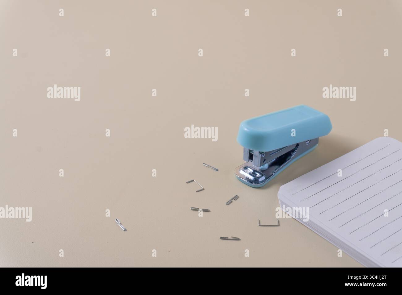 Agrafeuse avec des agrafes dispersées à côté d'une pile de papier nette prête à être coupée. Une scène de travail de bureau quotidien capturée sous un angle élevé Banque D'Images