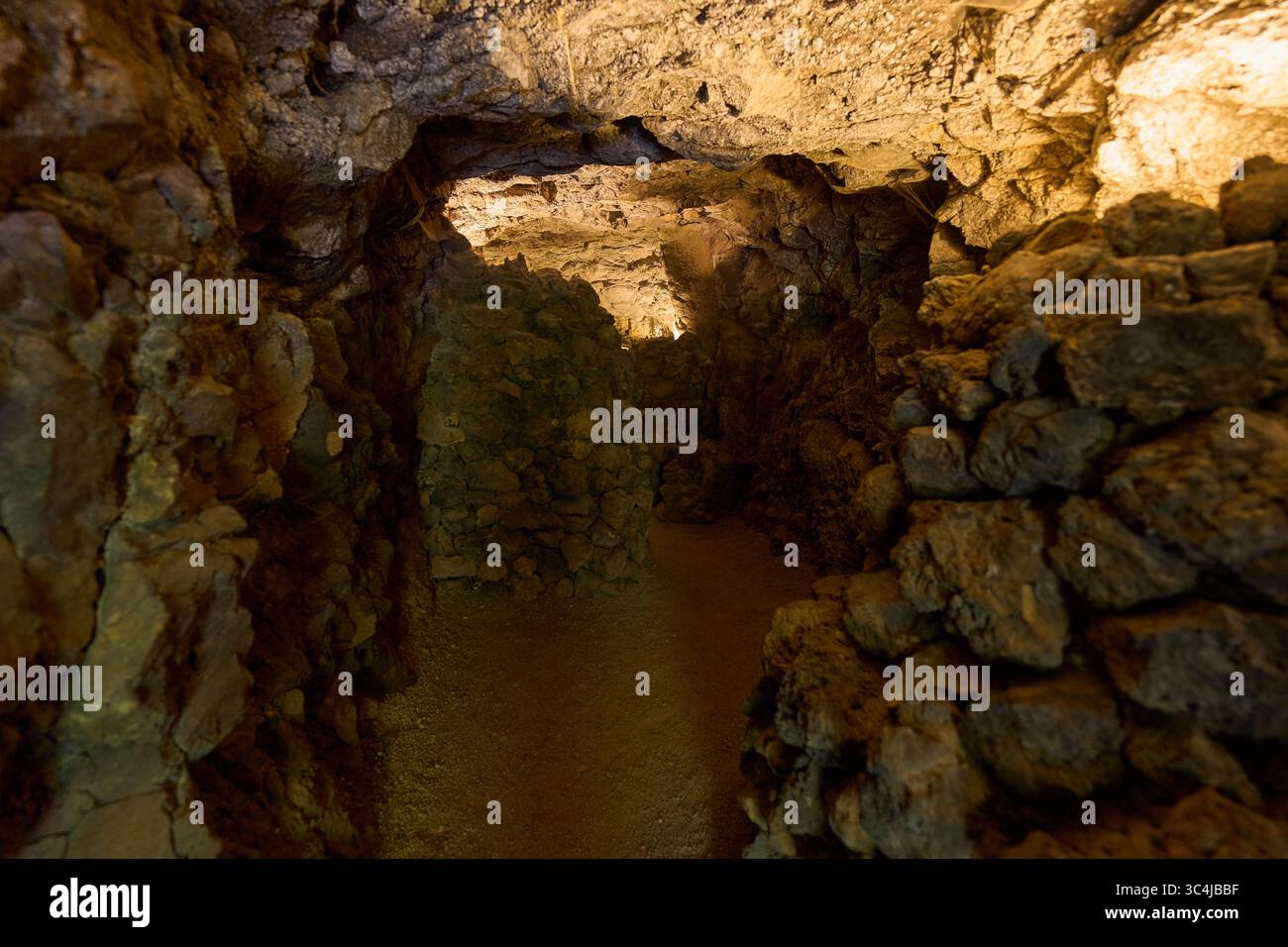Intérieur d'une grotte volcanique formée par un ancien tube de lave avec des murs en pierre brute et un éclairage tamisé Banque D'Images