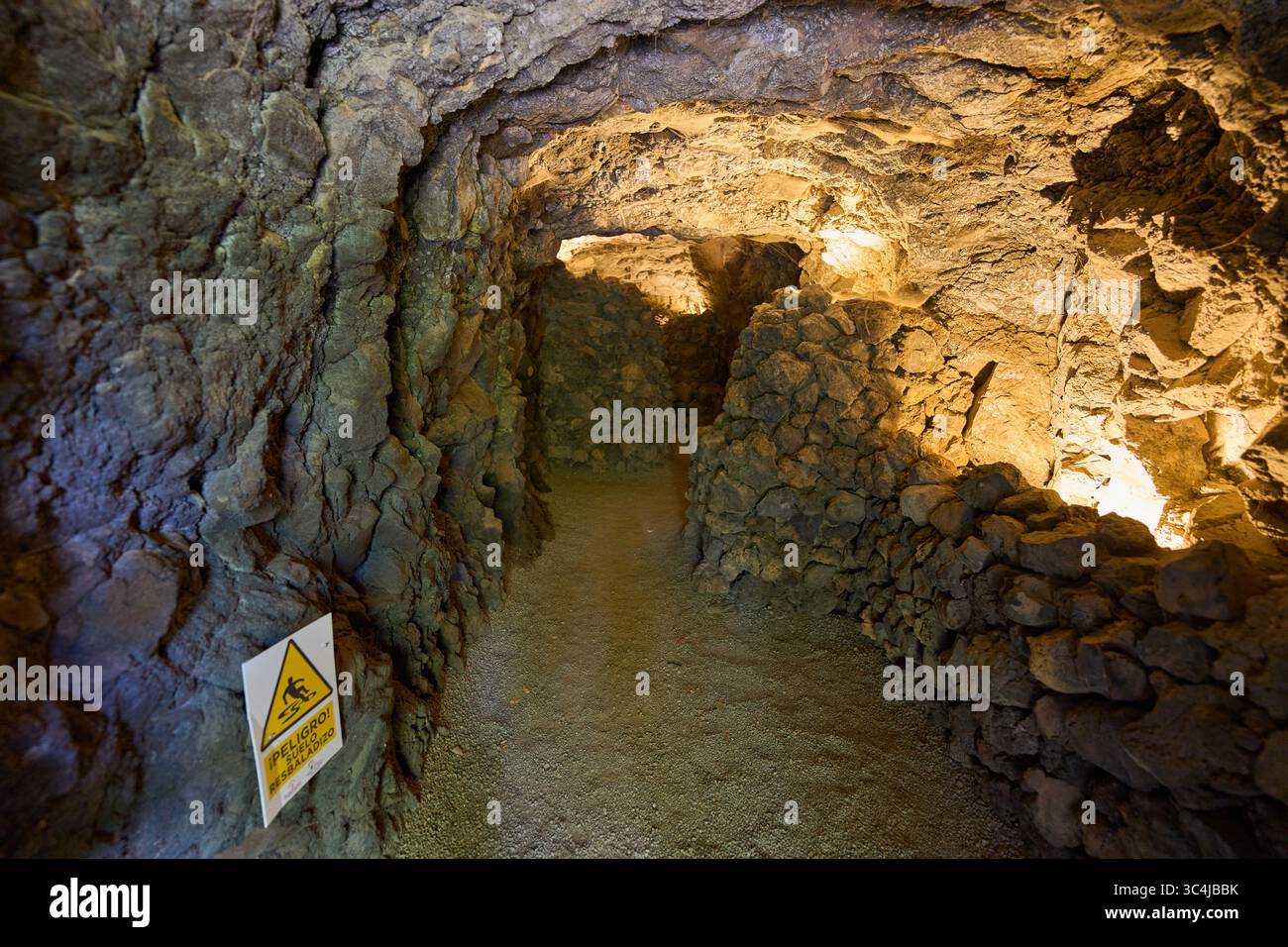 Intérieur d'une grotte volcanique formée par un ancien tube de lave avec des murs en pierre brute et un éclairage tamisé Banque D'Images